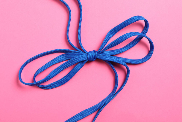 Blue shoelaces on pink background, top view - 写真・画像