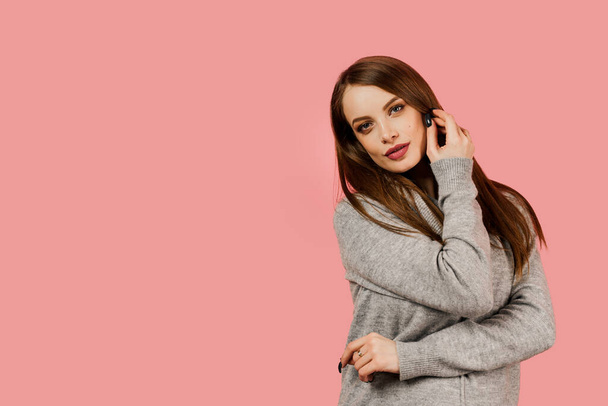 Professioneel model poseren in de studio. Lifestyle van Kaukasisch gelukkig meisje. Beauty portret van een vrouw droeg grijze trui op roze achtergrond. - Foto, afbeelding