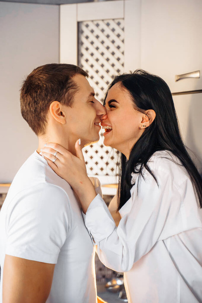 Nude passionate kissing couple. Guy and woman having intimate sex. Erotic moments of young lovers. Hot baby gently kisses her beloved man, leaning on the kitchen furniture.The 14th of February. - Photo, Image