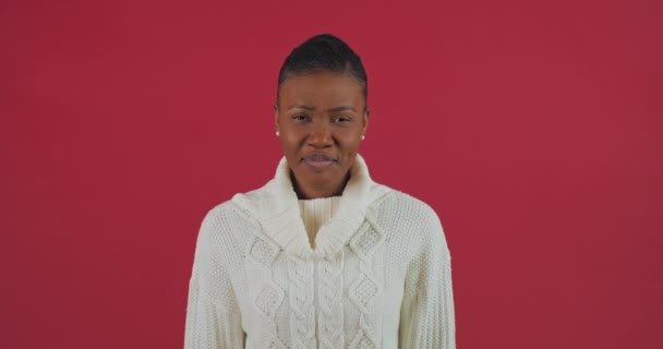 Portrét ženy smutné rozmrzelý obličej lidské emoce zlo odmítnutí, Afroameričanka dívka v bílém svetru stojí pózovat na červeném pozadí studio křik z stresu problémy s tlakem - Záběry, video