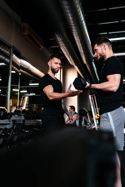 Personal trainer helping, assisting client in the gym and doing workout. Healthy lifestyle fitness session with personal traine - Фото, зображення