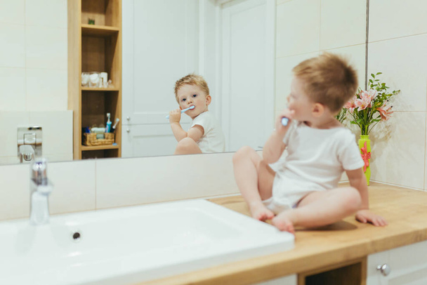 Little kid boy brushing teeth in his bathroom, baby taking care of teeth - Fotó, kép