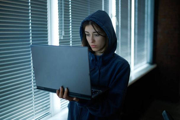 Mujer hacker de Internet en la capucha funciona en el ordenador portátil - Foto, imagen