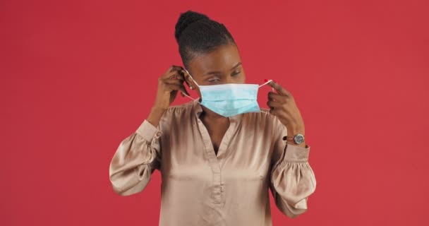 Studio žena portrét afro americká pozitivní žena etnická dívka pacient nošení lékařské chirurgické masky na obličeji ukazuje palce nahoru dává jako souhlas gesto souhlas doporučuje nosit respirátory - Záběry, video