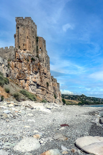 La playa de Roseto Capo Spulico con agua turquesa y un castillo sobre ella - Foto, Imagen
