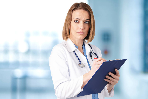Shot of middle aged female doctor holding clipboard  - Foto, immagini