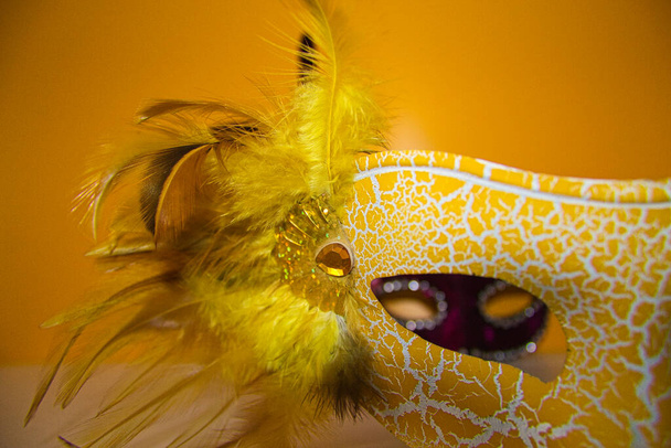 žlutá karnevalová maska a skrz ní můžete vidět fialovou karnevalovou masku - Fotografie, Obrázek