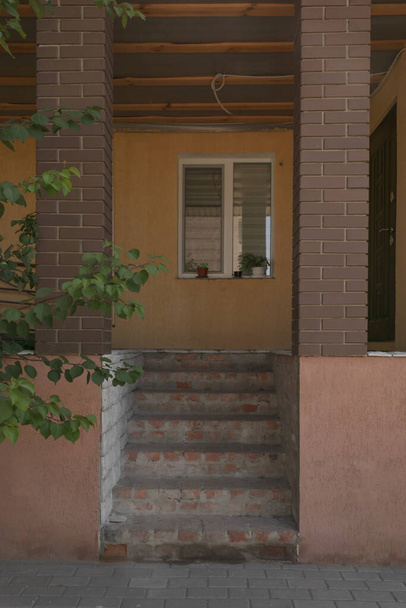 По бокам бетонная лестница с двумя коричневыми колоннами и окном вместо входа - Фото, изображение
