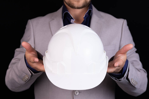 Engineer, builder, businessman in a white helmet on a dark background. Portrait. The concept of engineering, business, construction, urban life and the future. - Foto, imagen