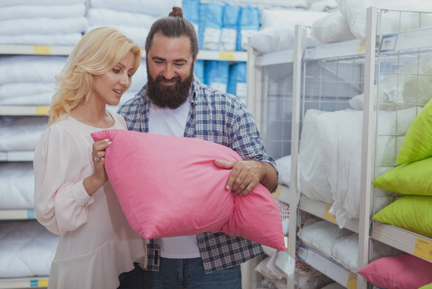 Healthy sleep concept. Happy mature couple choosing new pillows for their bedroom, shopping at furnishings store. Husband and wife buying orthopedic pillow at department store - Foto, Imagem