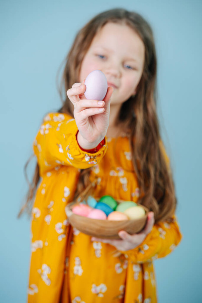 Happy gentle little girl holding easter eggs over blue - Фото, изображение