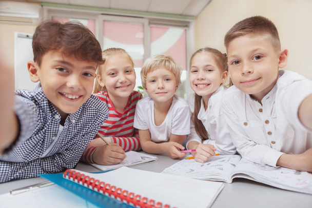 Childhood, school lifestyle concept. Group of adorable happy kids taking a selfie together at class. Cheerful little schoolchildren smiling to the camera, taking a selfi - Fotoğraf, Görsel