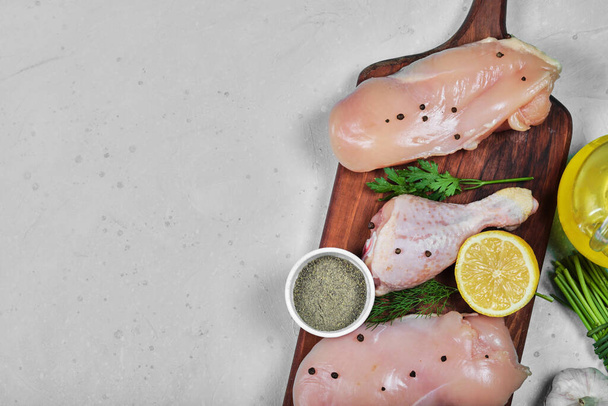 Filete de pollo crudo y patas en plato de madera con verduras frescas y especias - Foto, imagen