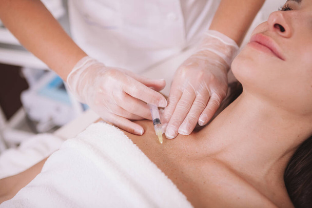 Cropped shot of a woman getting hyaluronic acid injections in her chest skin. Female client getting skin tightening treatment at beauty clinic - Фото, изображение