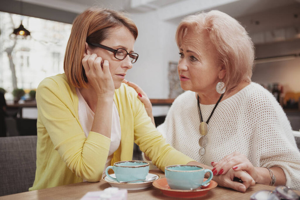 Senior woman comforting her upset adult daughter. Depressed mature woman meeting her elderly mother - Фото, изображение