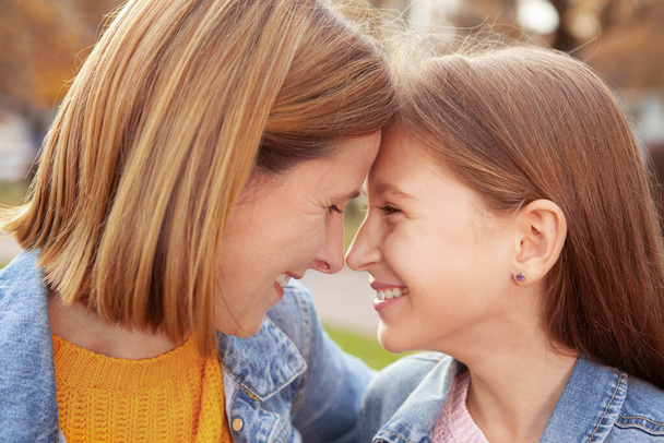 Close up of happy mother and daughter laughing, touching with foreheads - Foto, Imagem