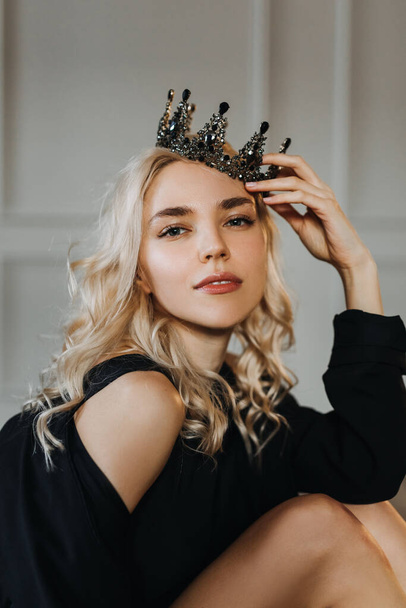 Portrait d'une jeune femme blonde sensuelle, portant une couronne noire, regardant la caméra. - Photo, image