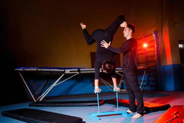 Fiatal nő és férfi tornászok akrobatikus gyakorlatokat végeznek az edzőteremben. Sport tevékenységek, egészséges életmód - Fotó, kép