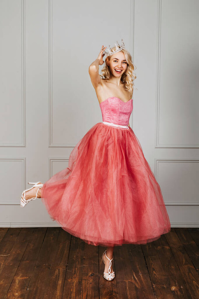Happy young woman wearing a pink tulle dress and a crown, smiling. - Foto, Imagen