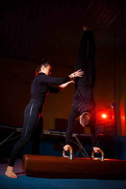 Ein Akrobaten-Duo, das einen doppelten Trick vorführt. Eine Frau in Turnhosen und ein Mann in Sportbekleidung. Sehr flexible Zirkuskünstler. - Foto, Bild