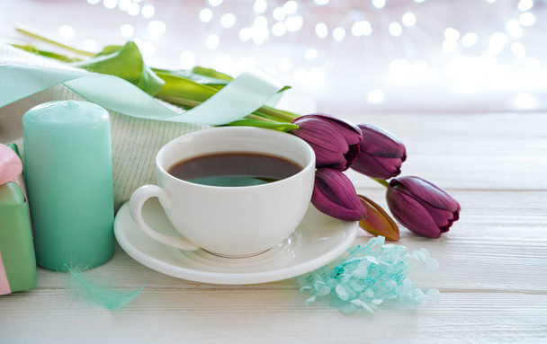 Una taza de café, velas, flores sobre un fondo claro con una guirnalda ardiente. - Foto, Imagen