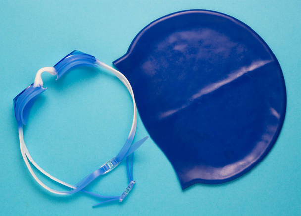 bleu bonnet de bain bébé lunettes de bébé pour la piscine, fond bleu. leçon de natation, mode de vie sain. espace de copie. - Photo, image