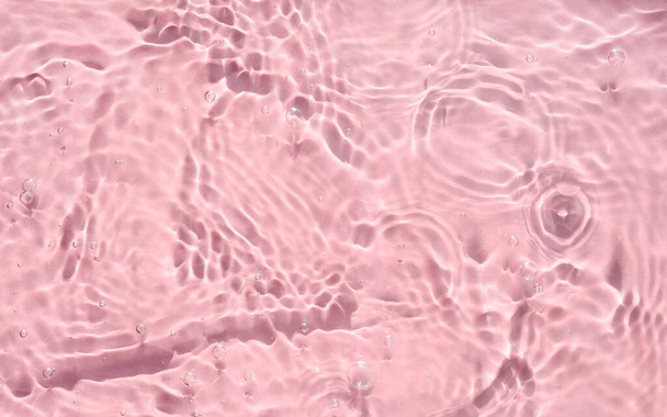 波紋、波と泡とピンクの水のテクスチャ。テクスチャ水表面上の太陽の反射や影の閉鎖。トレンディ抽象的な夏の背景、波打つスイミングプール - 写真・画像