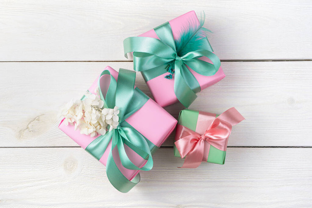 Pink gift boxes with ribbons on a white wooden background. Top view, with space to copy. - Photo, Image