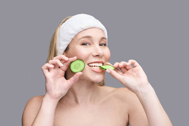 Cosmetology concept. Skin care product. Female portrait. Cucumber face mask. - Foto, afbeelding