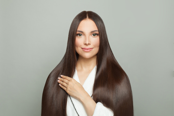 Krásná žena s dlouhými zdravými rovnými vlasy na bílém pozadí. Koncept péče o vlasy - Fotografie, Obrázek