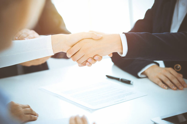 Business people shaking hands finishing up meeting or negotiation in sunny office. Business handshake and partnership concepts - Photo, Image