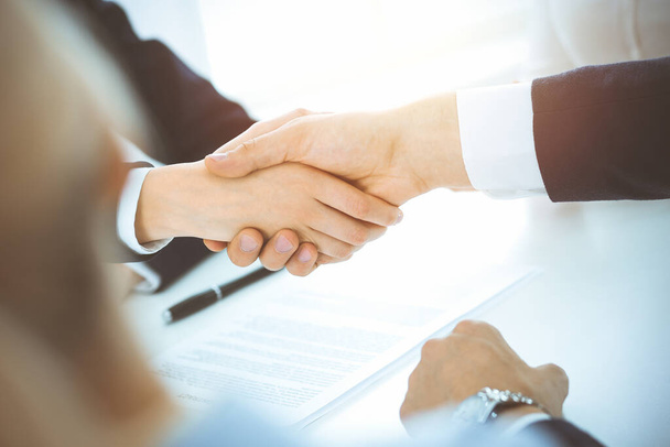 Business people shaking hands finishing up meeting or negotiation in sunny office. Business handshake and partnership concepts - Photo, Image