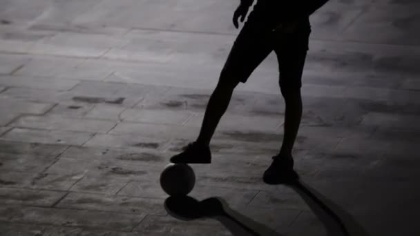 La silueta de un hombre que juega al fútbol de noche contra el fondo de la ciudad - 4K - Metraje, vídeo