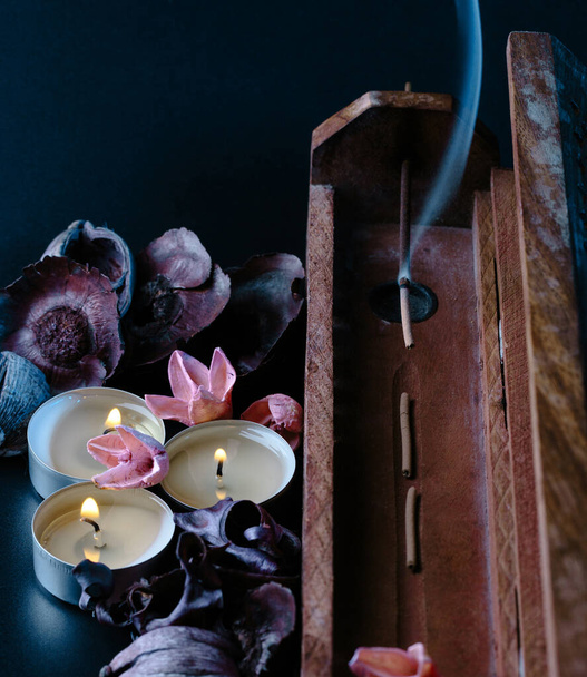 incense stick aroma with smoke  in a wooden handmade holder with dried petals and candles  isolated on background - Foto, Bild