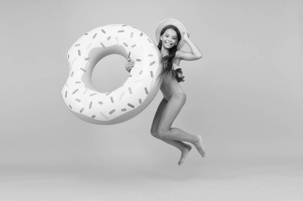 Cheerful kid relaxing. Relaxing at pool. Summer resort. Recreation concept. Hotel with swimming pool. Little girl and swimming donut ring. Kid in swimsuit relaxing and having fun. Summer vacation - Photo, image