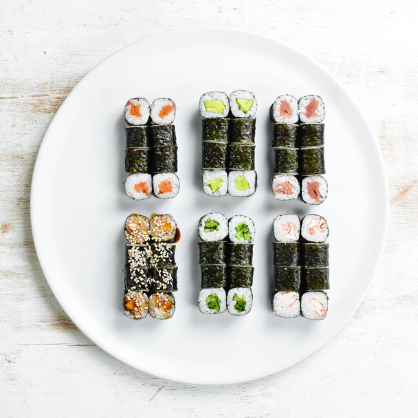 Traditional Japanese sushi rolls on a white plate. Top view. Asian food. On a white background. - Zdjęcie, obraz
