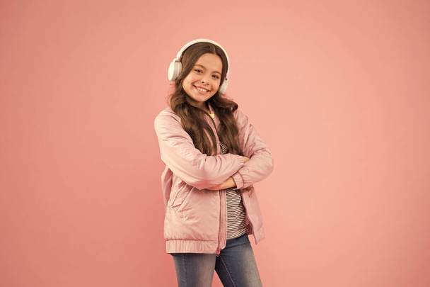 Enjoy sound. Sound vibrations. Music and technology. Audio sound. Singing along to tune. Happy child enjoy listening to sound track. Little girl wear earphones pink background - Foto, afbeelding