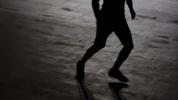 La silueta de un hombre que juega al fútbol de noche contra el fondo de la ciudad - 4K - Metraje, vídeo