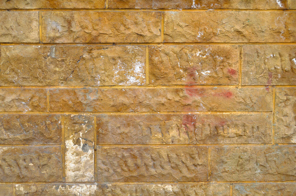 Erős sárga és bézs vágott kő fal, jó háttér, zökkenőmentes sorakozó - Fotó, kép