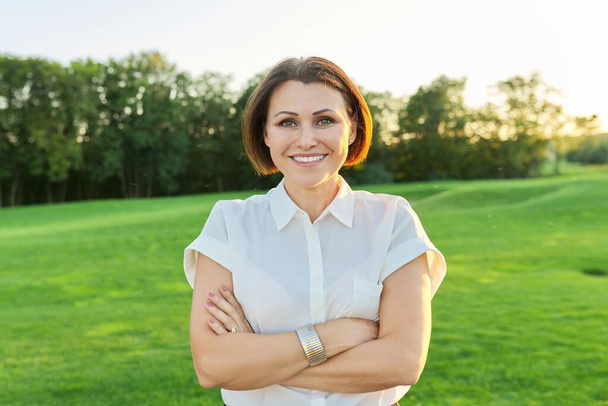 Outdoor portrait of happy middle age woman with crossed arms looking in camera - Foto, immagini
