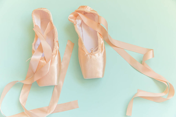 Nuove scarpe da balletto beige pastello con nastro di raso isolato su sfondo blu. Ballerina scarpe da punta classiche per allenamento di danza. Concetto di scuola di danza. Vista dall'alto lastra piatta spazio copia - Foto, immagini