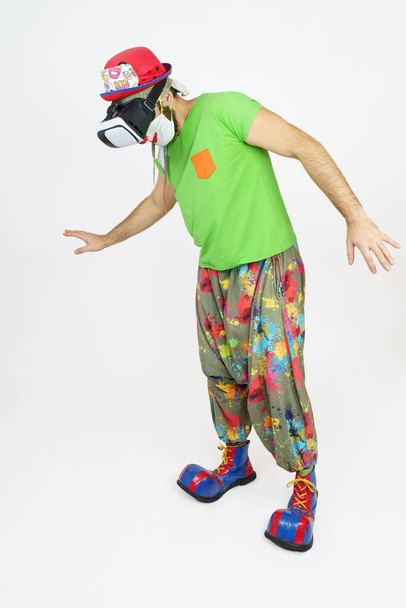 Holiday and fun concept. The clown plays, he has virtual glasses on his head, looks down. Isolated on white - Foto, Imagem