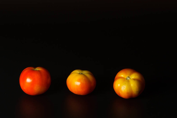 Unripe small tomatoes, isolate on a black background. Horizontally with space - Photo, Image