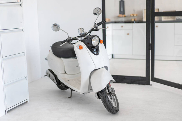 White retro moped standing indoor Vintage scooter stands indoors as interior decoration Nobody - Foto, Imagem