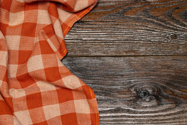 Checkered linen tablecloth on a wooden background. Brown wooden table. Selective focus. Copy space. Place for food and drink. Picnic and thanksgiving day concept - Photo, Image