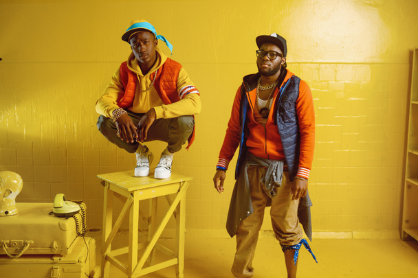 Two stylish rappers in studio, yellow background - Foto, immagini