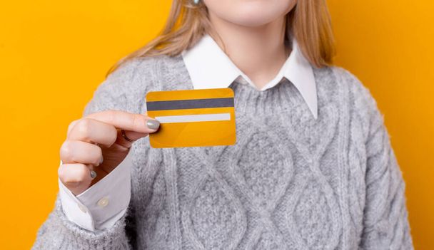 Concentration sélective de la main de la femme montrant la carte de crédit jaune - Photo, image