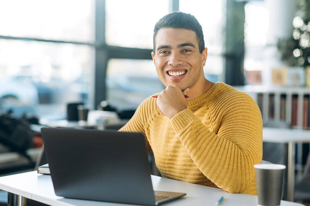 Portrait of happy successful business man at the workplace. Joyful hispanic male freelancer or student sit at the work desk in office, look directly at the camera and smiling - Foto, Imagem