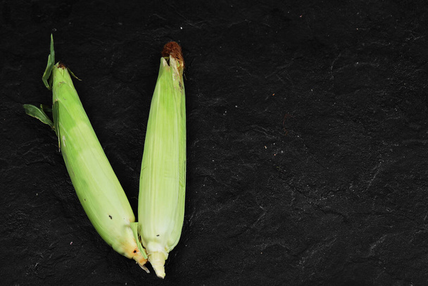 Dos espigas de maíz fresco sobre fondo negro - Foto, Imagen