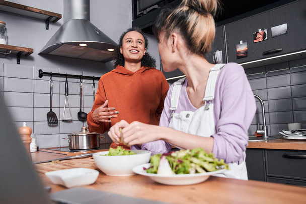 Woman chatting with her bestie while preparing salad - Foto, Imagem